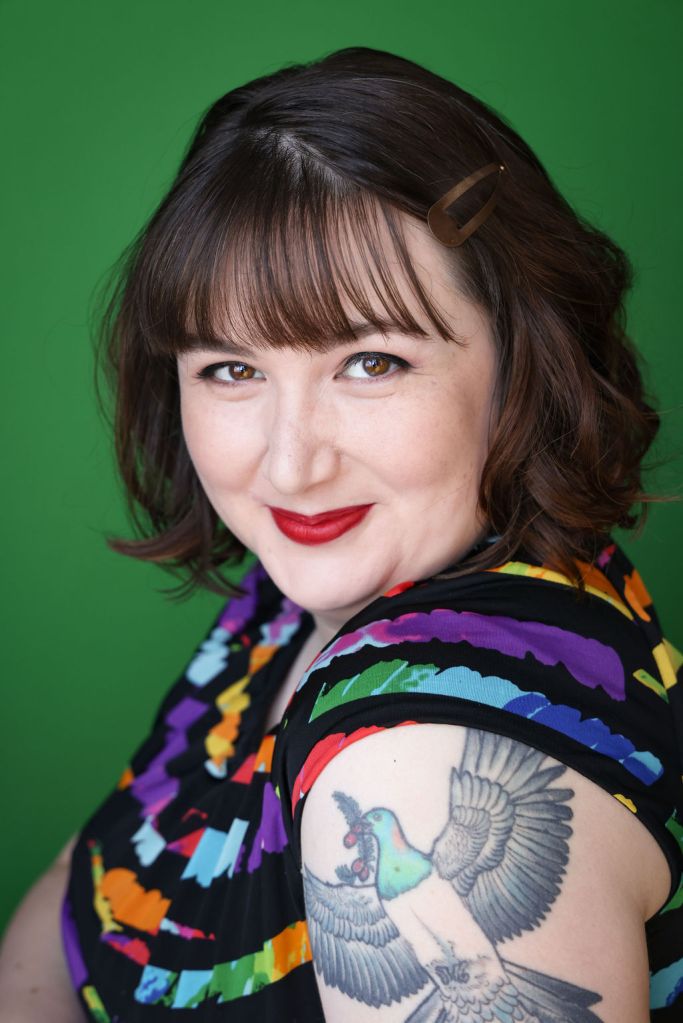 Photo of a lovely brunette person with feminine features from the chest up, partially in profile with their face towards the camera. The label reads Kara Moon.