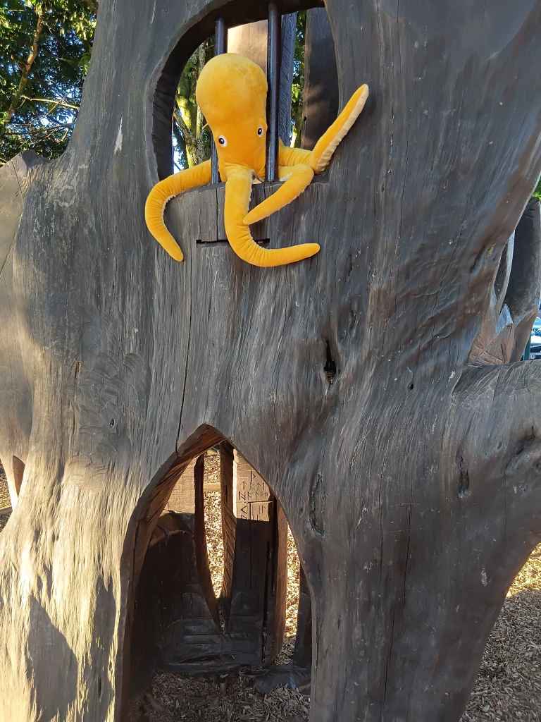 A plush octopus behind bars in a tree-playhouse